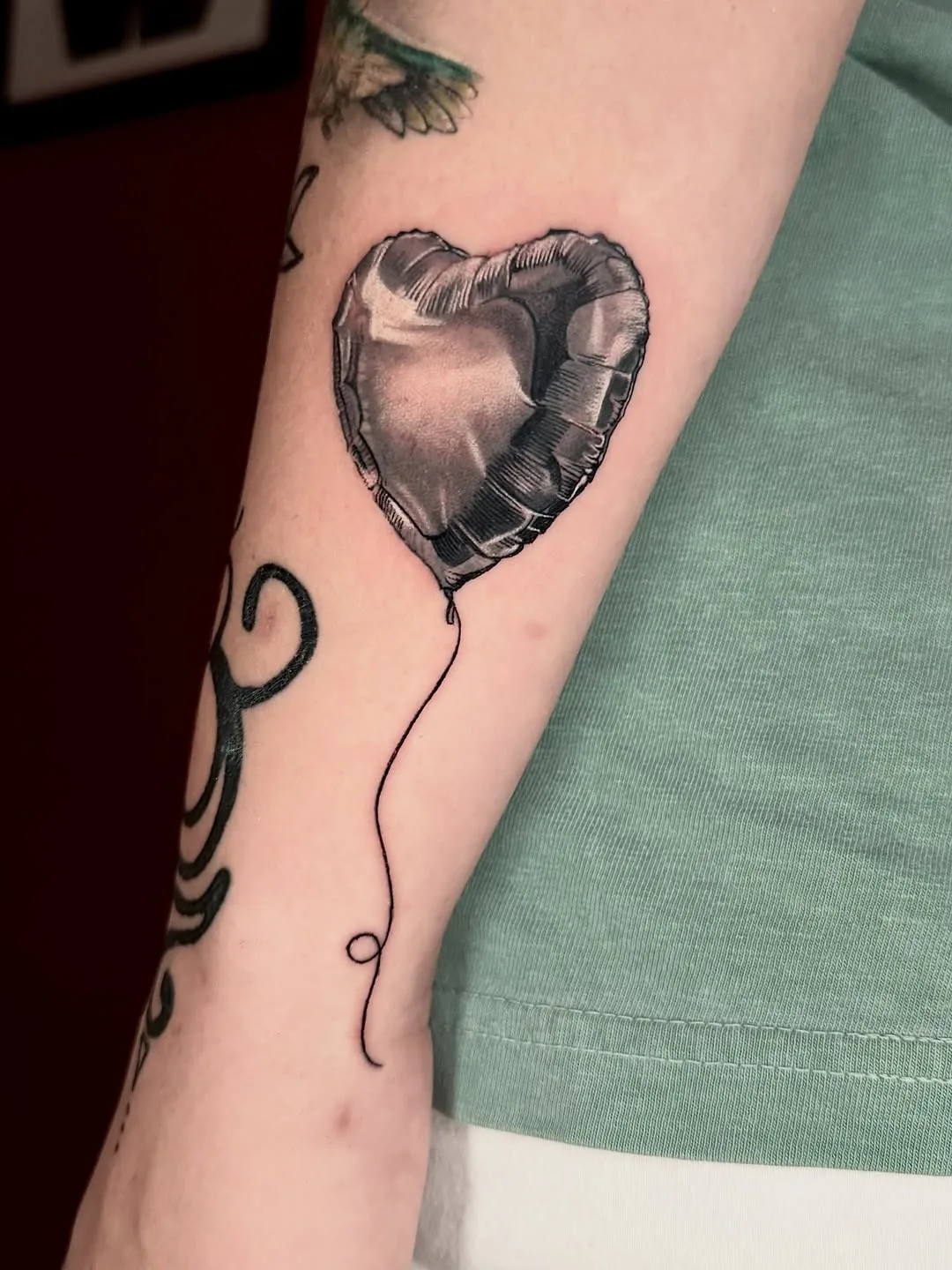 Chrome broken-heart balloon tattoo in black and grey