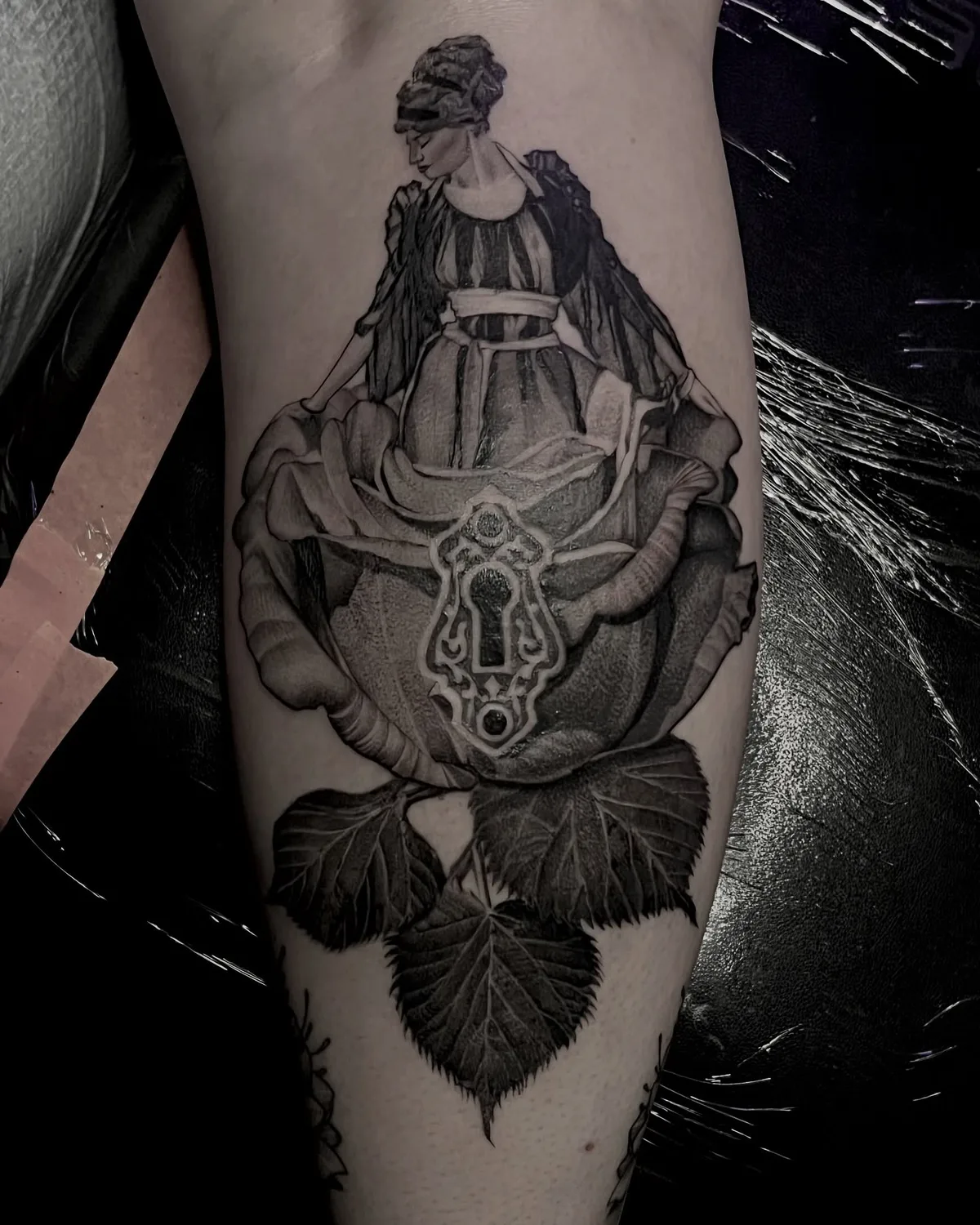 Surreal woman emerging from a rose with an antique keyhole, black and grey calf tattoo