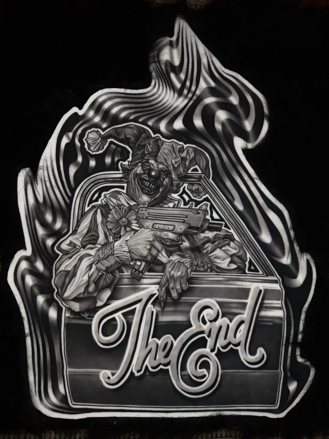 Jester clown with machine pistol in a lowrider, airbrushed lettering reading The End, tattooed on fake skin